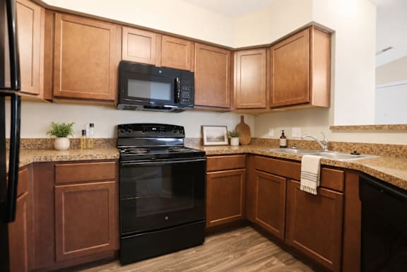 A kitchen with wooden cabinets and black appliances.
