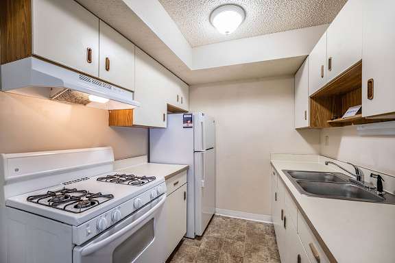 A kitchen with a white stove and refrigerator at Seville Apartments, Kalamazoo, 49009