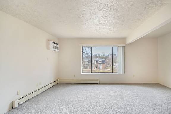 A spacious living room with a window and a carpeted floor at Seville Apartments, Michigan