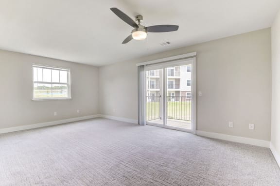 an empty living room with a ceiling fan and a door to a balcony  at Signature Pointe Apartment Homes, Alabama, 35611
