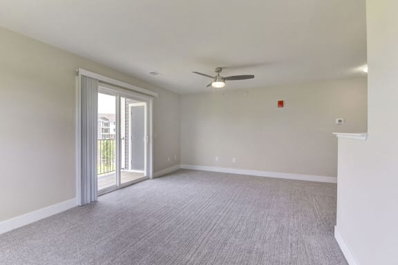 an empty living room with a ceiling fan and a door to a balcony  at Signature Pointe Apartment Homes, Alabama
