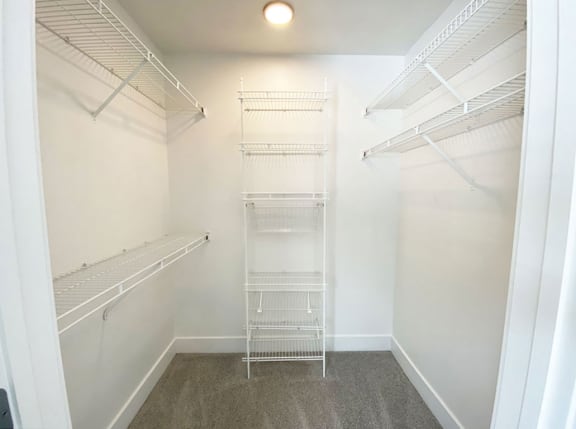 a walk in closet with white shelves and a white closet door  at Signature Pointe Apartment Homes, Athens, AL, 35611