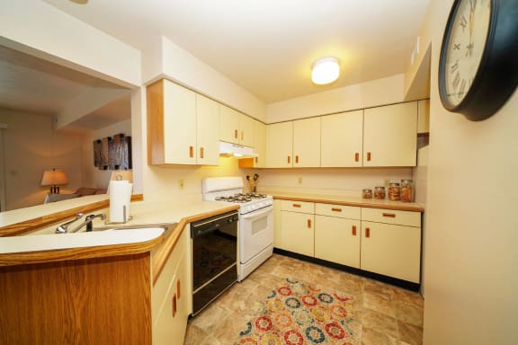 a kitchen with white cabinets and a stove and a sink at South Bridge Apartments, Fort Wayne, IN