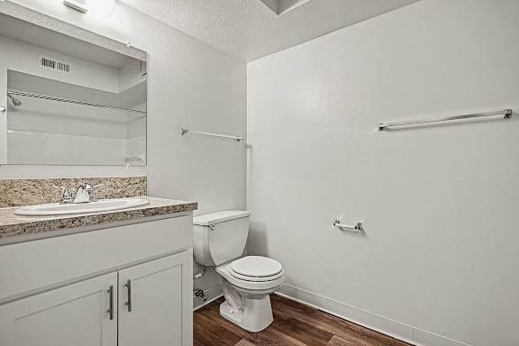 A white toilet sits in a bathroom next to a sink.