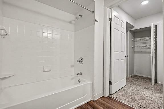 A white bathroom with a walk-in shower and a white door.