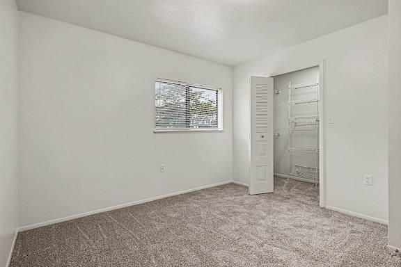 A room with a carpeted floor and a window with blinds.