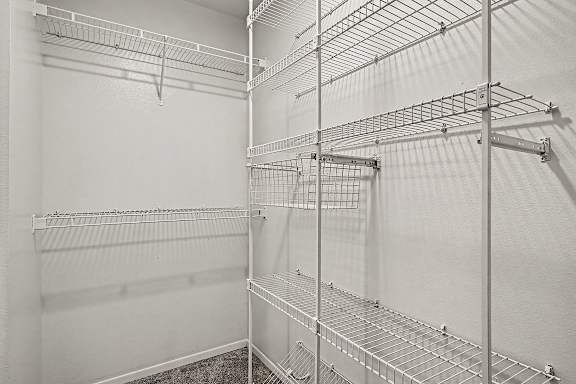 A white walk in closet with shelves and hooks.