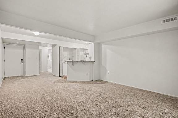 A sparsely furnished room with a carpeted floor and white walls.