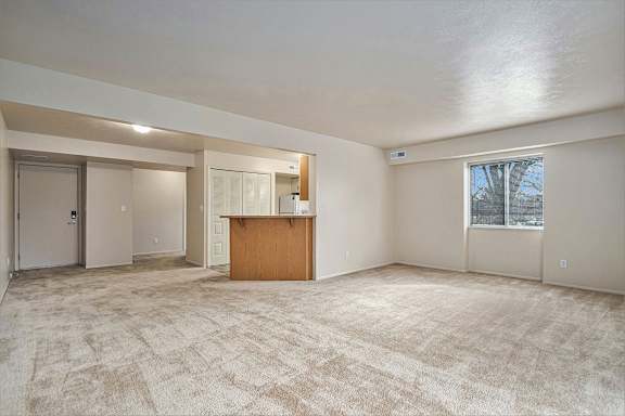 A spacious room with a carpeted floor and a wooden cabinet in the middle.