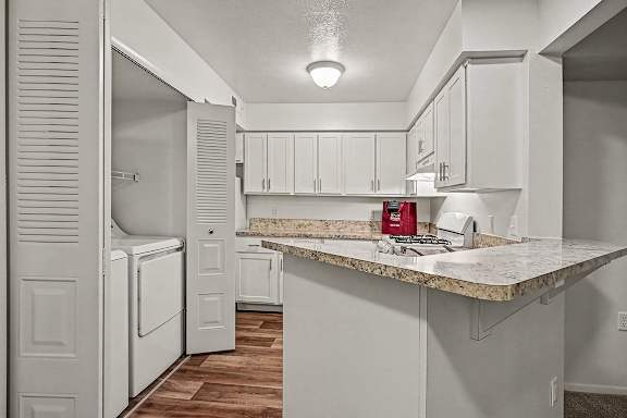 A kitchen with white cabinets and a marble countertop.
