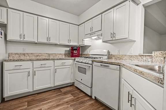 A kitchen with white cabinets and appliances.