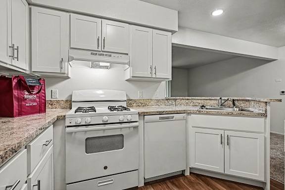 A kitchen with a white stove and cabinets.