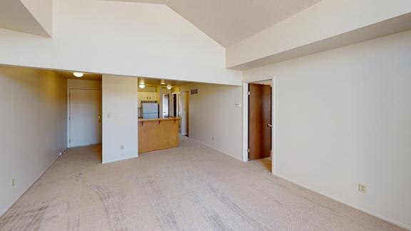 A large living room with a cathedral ceiling and a kitchen with breakfast bar at South Bridge Apartments, Fort Wayne, Indiana