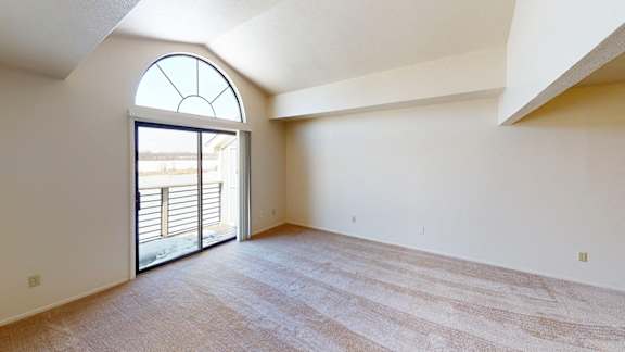 A living room with a cathedral ceiling and a slider to a balcony at South Bridge Apartments, Fort Wayne, Indiana