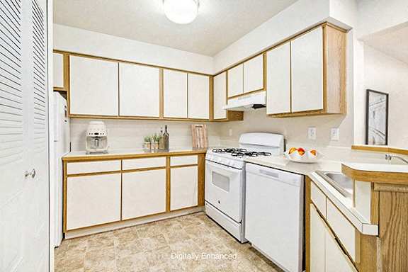 A kitchen with white appliances and wooden cabinets at South Bridge Apartments in Fort Wayne, IN