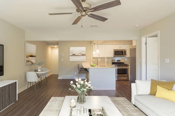 a living room with a white couch and a table with a vase of flowers on it at Hillside Apartments, Wixom, 48393