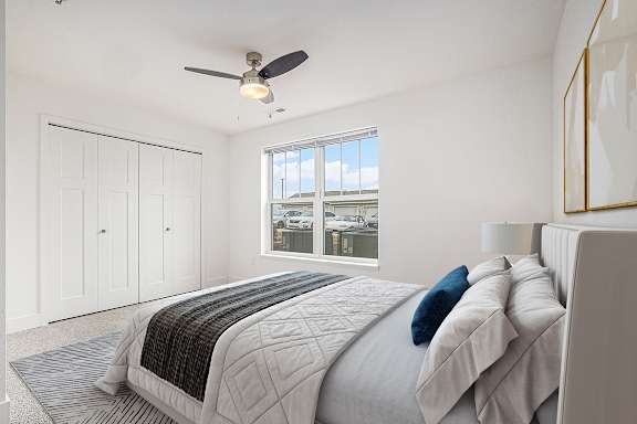 a white bedroom with a large window, walk-in closet and a ceiling fan at Stoney Pointe Apartment Homes, Wichita
