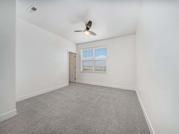 A spacious bedroom with a ceiling fan, carpeted floor and walk-in closet at Strathmore Apartment Homes in West Des Moines, IA