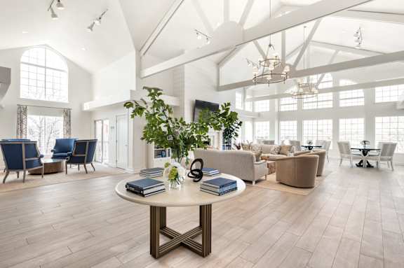 A spacious room with a round table in the center and chairs surrounding it.