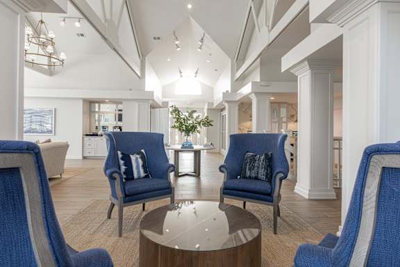 A modern living room with blue chairs and a glass table.