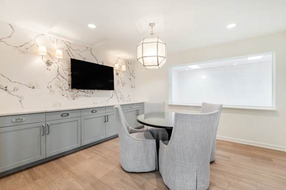 A modern living room with a television, grey armchairs, and a marble backsplash.