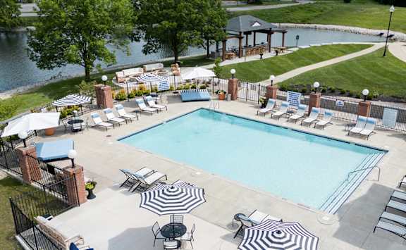 A large outdoor swimming pool surrounded by lounge chairs and umbrellas.