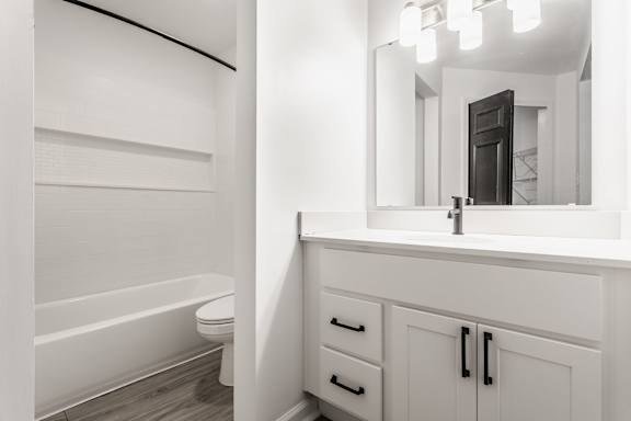 A white bathroom with a tub, sink, and mirror.