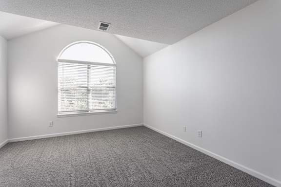 A room with a large window and carpeted floor.