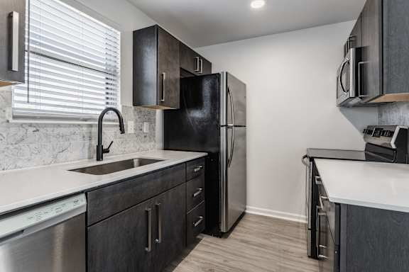 A kitchen with a black fridge and a white counter top.