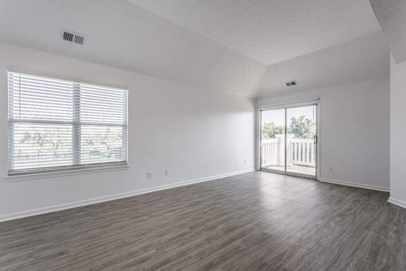 A room with wooden flooring and a window with blinds.