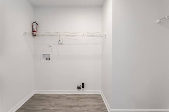 A white room with a fire extinguisher on the wall.
