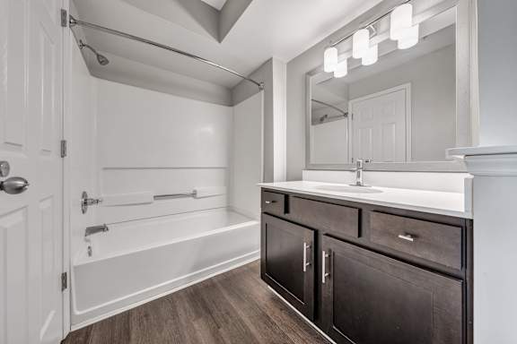 A bathroom with a white tub, sink, and mirror. at Sunscape Apartments, Virginia