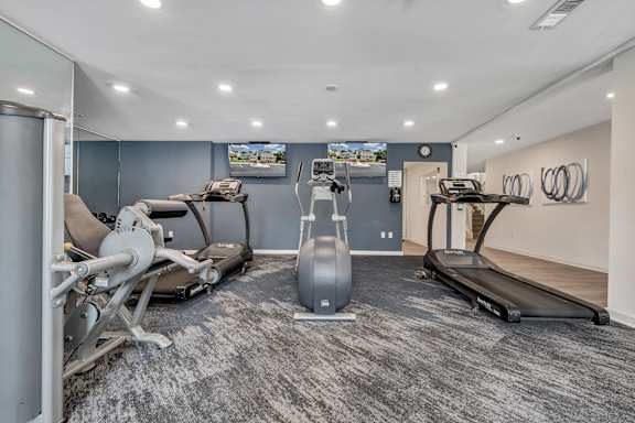 A gym with a treadmill, exercise bike, and weight machine. at Sunscape Apartments, Roanoke