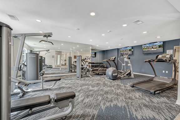 A spacious gym with a variety of equipment including treadmills, weight machines, and a rowing machine. at Sunscape Apartments, Roanoke, Virginia