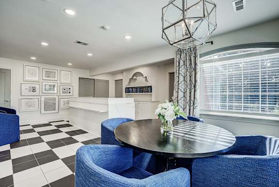 A black and white checkered floor in a room with blue chairs and a round table. at Sunscape Apartments, Virginia
