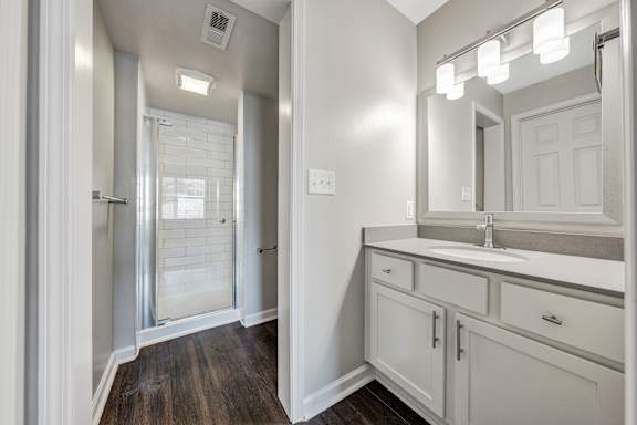 A bathroom with a sink, mirror, and a shower with a glass door. at Sunscape Apartments, Roanoke, 24018