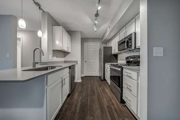 A modern kitchen with white cabinets and a wooden floor. at Sunscape Apartments, Roanoke, Virginia
