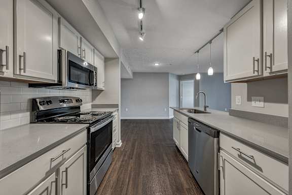 A modern kitchen with dark wood floors and white cabinetry. at Sunscape Apartments, Virginia, 24018
