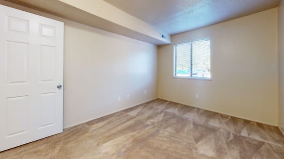 an empty living room with a white door and a window