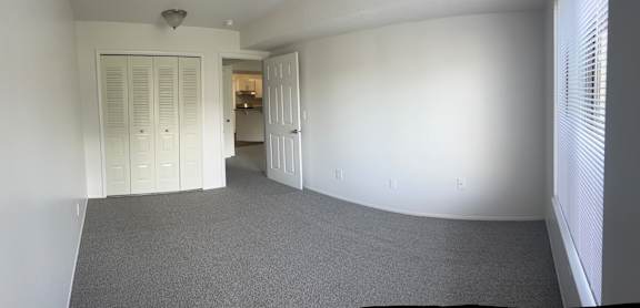 A long hallway with white walls and a carpeted floor