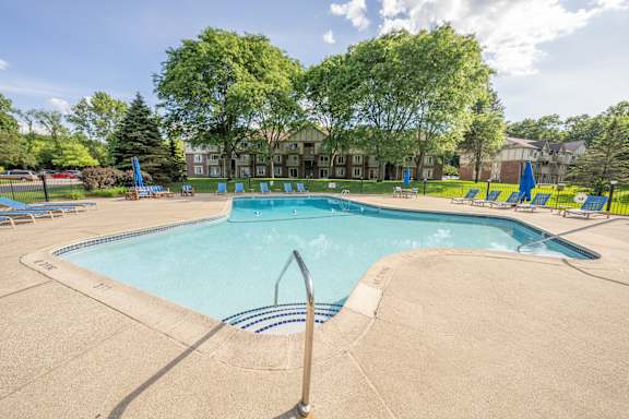 A large swimming pool surrounded by trees and lounge chairs.