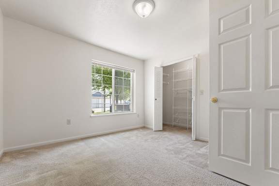 A bedroom with a large window, walk-in closet and carpet at Tall Oaks Apartment Homes, Kalamazoo, MI, 49009