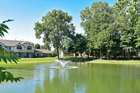 a fountain in a pond with houses in the background at Tanglewood Apartments, Oak Creek, WI, 53154