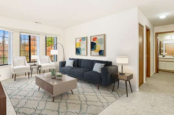 A living room with a bay window,  grey couch, and a coffee table  at Tanglewood Apartments, Oak Creek, WI