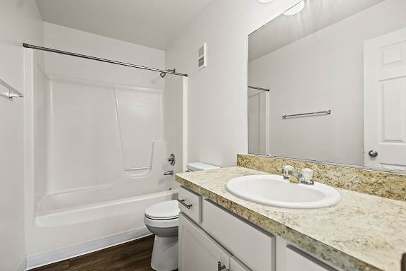 A white bathroom with a sink, toilet, and bathtub at Tanglewood Apartments, Oak Creek, WI