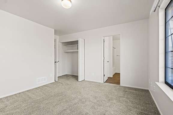 A bedroom with a large closet and carpeted floor and white walls at Tanglewood Apartments, Oak Creek, WI