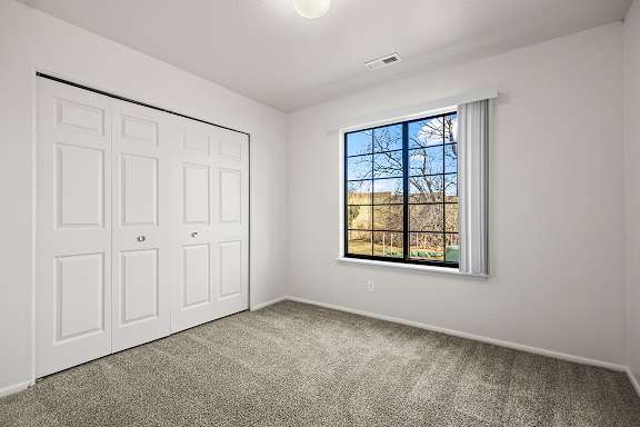 A bedroom with a large window and closet at Tanglewood Apartments, Oak Creek, WI