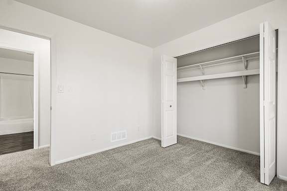 A white bedroom with a large closet and carpeted floor at Tanglewood Apartments, Oak Creek, WI