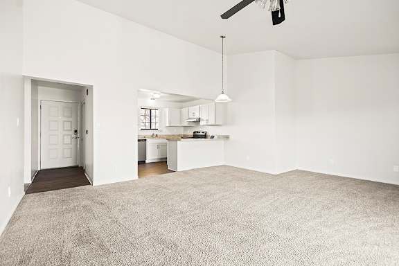 A large, empty living and dining room with a ceiling fan and a kitchen area in the background at Tanglewood Apartments, Oak Creek, WI