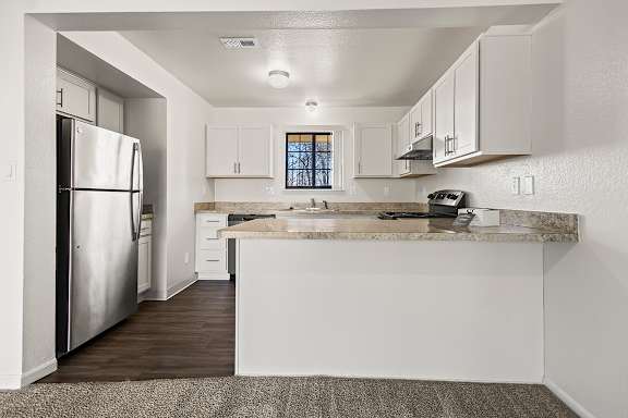 A kitchen with a stainless steel refrigerator and a breakfast bar at Tanglewood Apartments, Oak Creek, WI